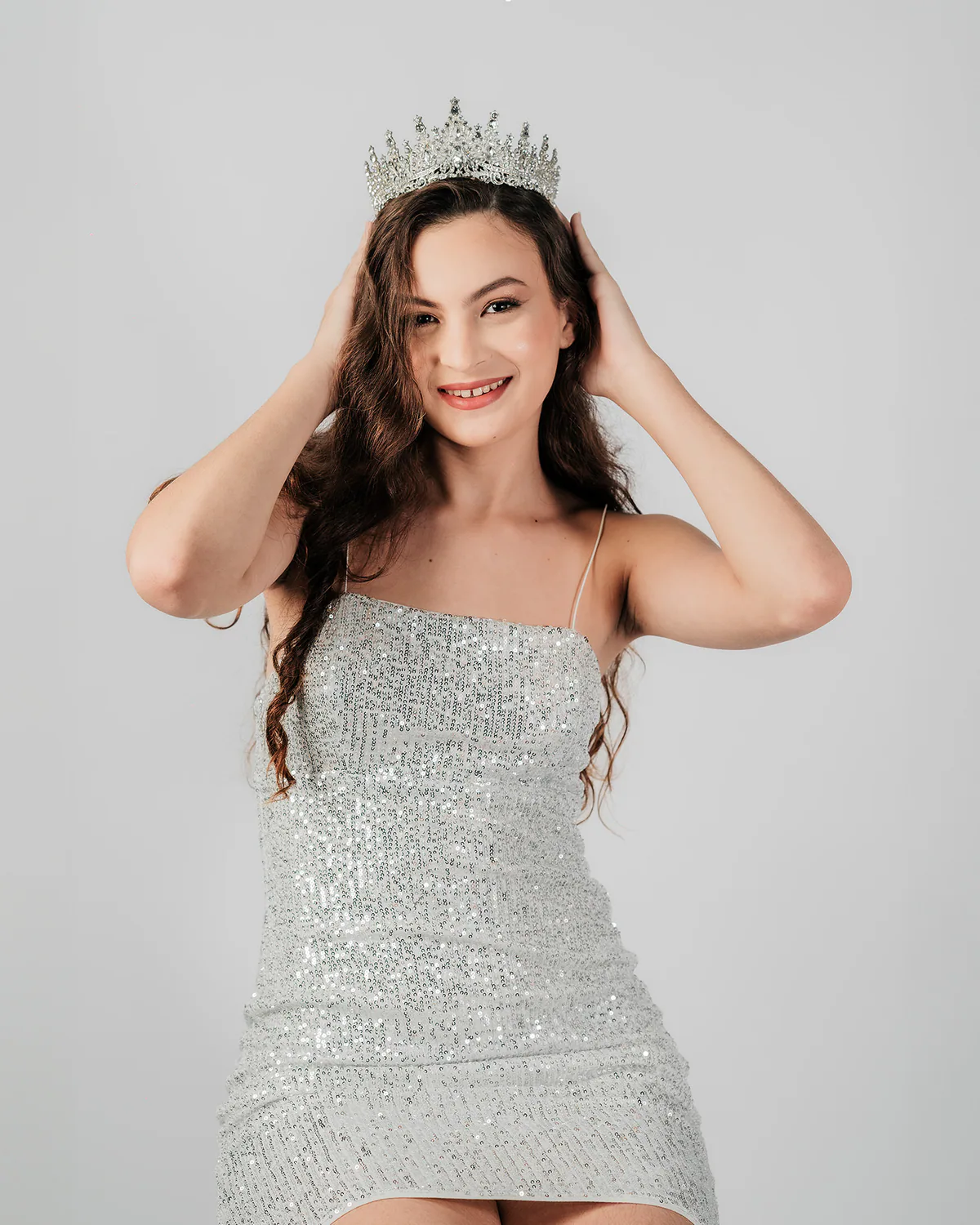 Debutante com vestido prateado e coroa durante ensaio no estúdio