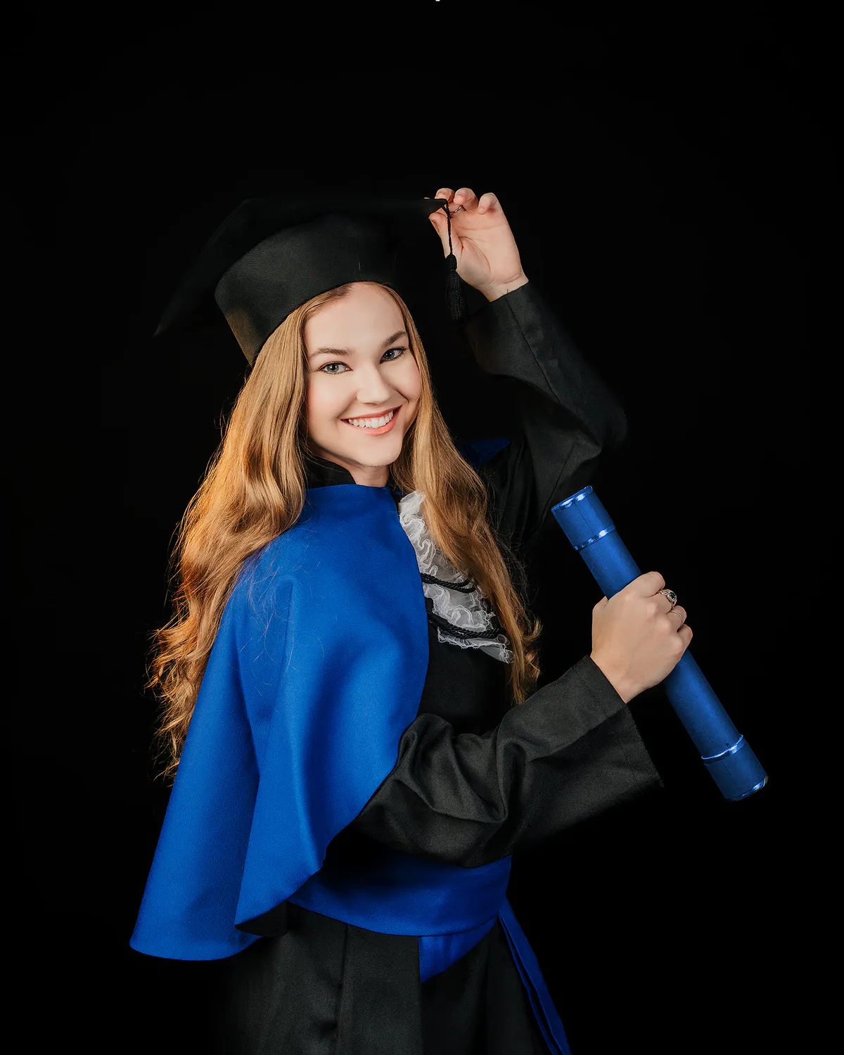 Formanda com beca azul, capelo e diploma durante ensaio de formatura