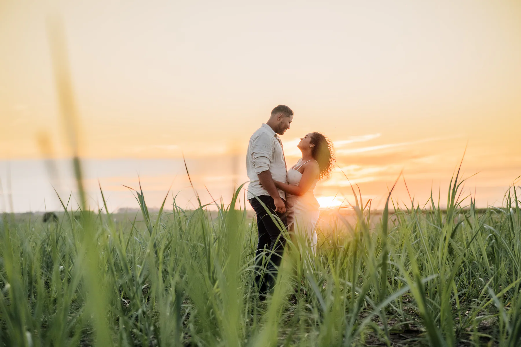 Casal se abraça ao pôr do sol durante ensaio no campo